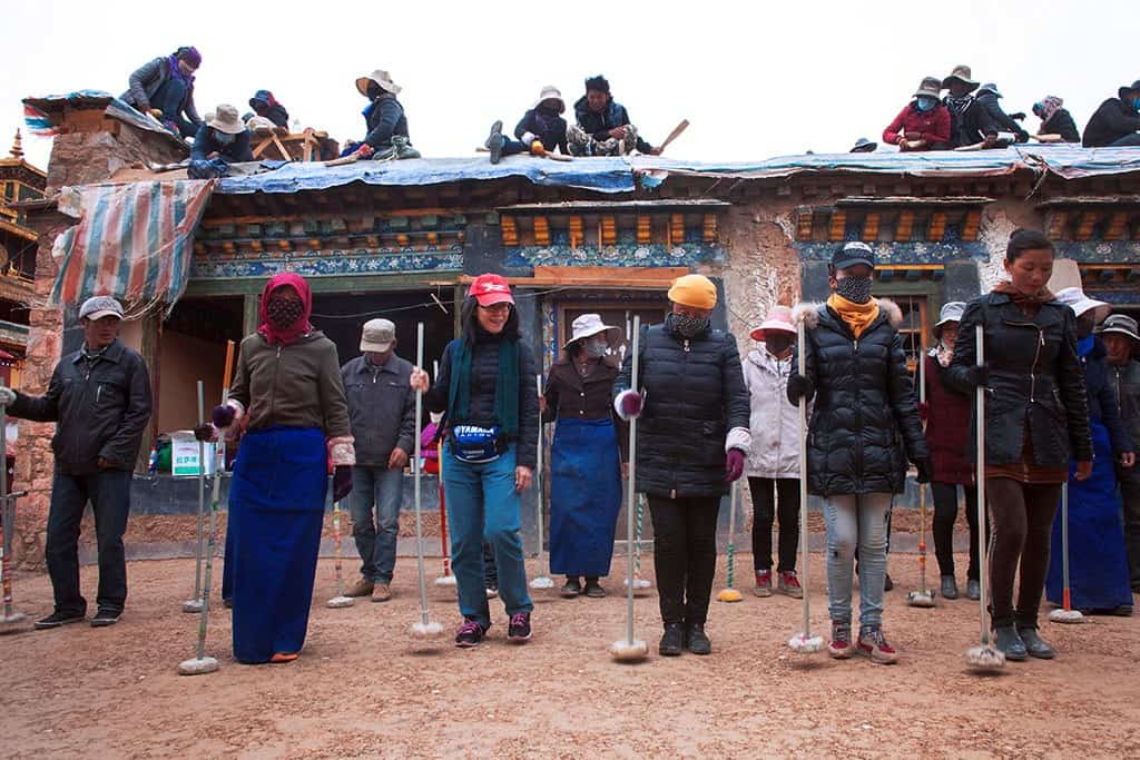 藏族朋友手握着“帛多”列成一排，嘴里哼唱着劳动号子，随着歌声的节奏，夯打阿嘎土。