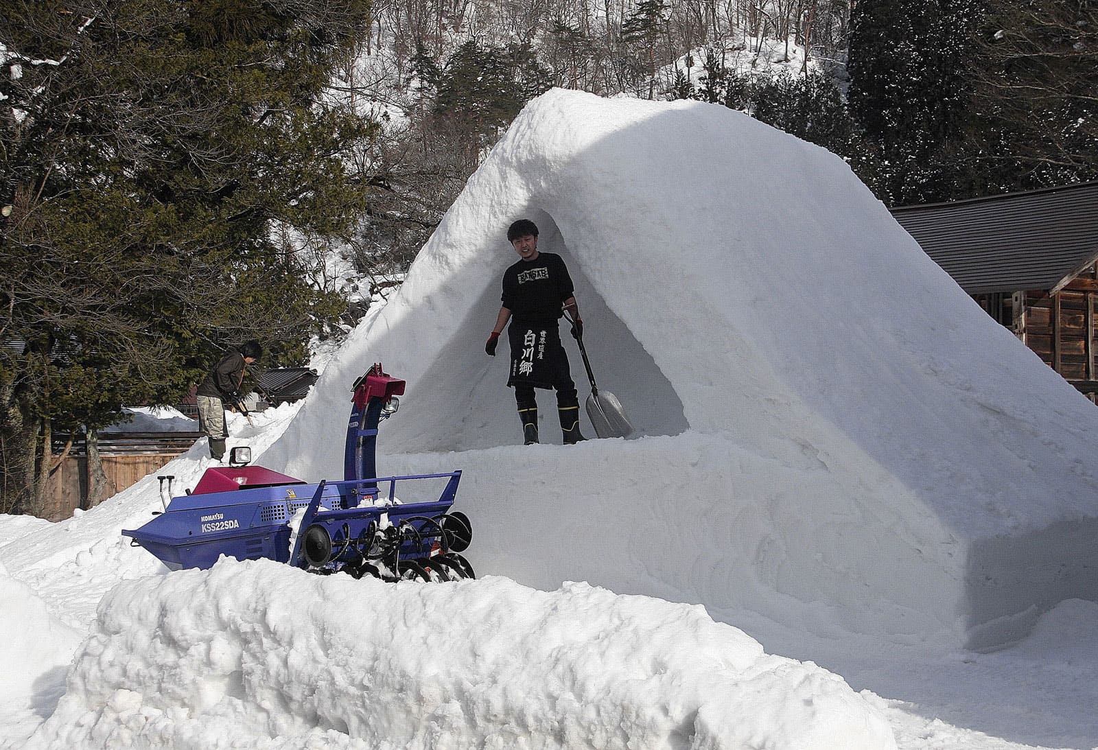 明天是点灯节，村民正用积雪堆个合掌屋顶的模型。